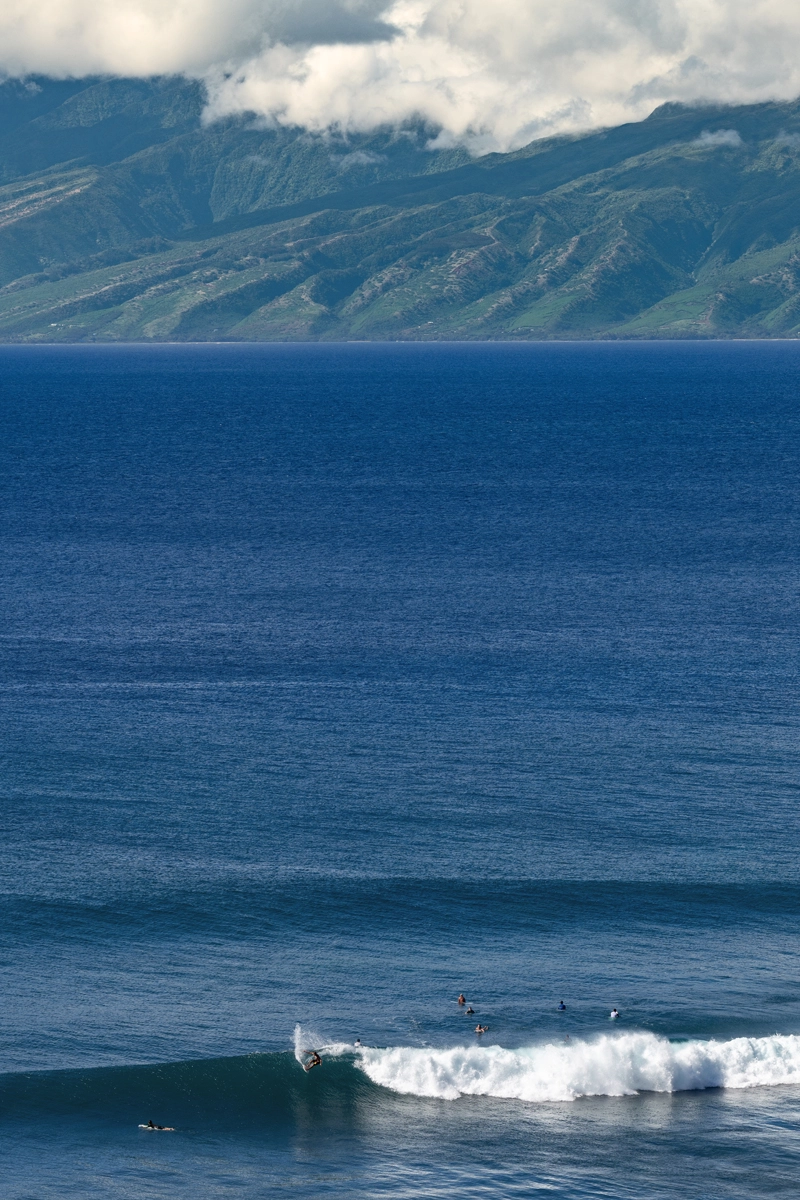 Surfers catching a wave off the coast of Maui, Hawaii.