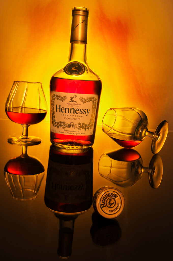 Glowing Hennessy Bottle with tipped glasses that are half-filled