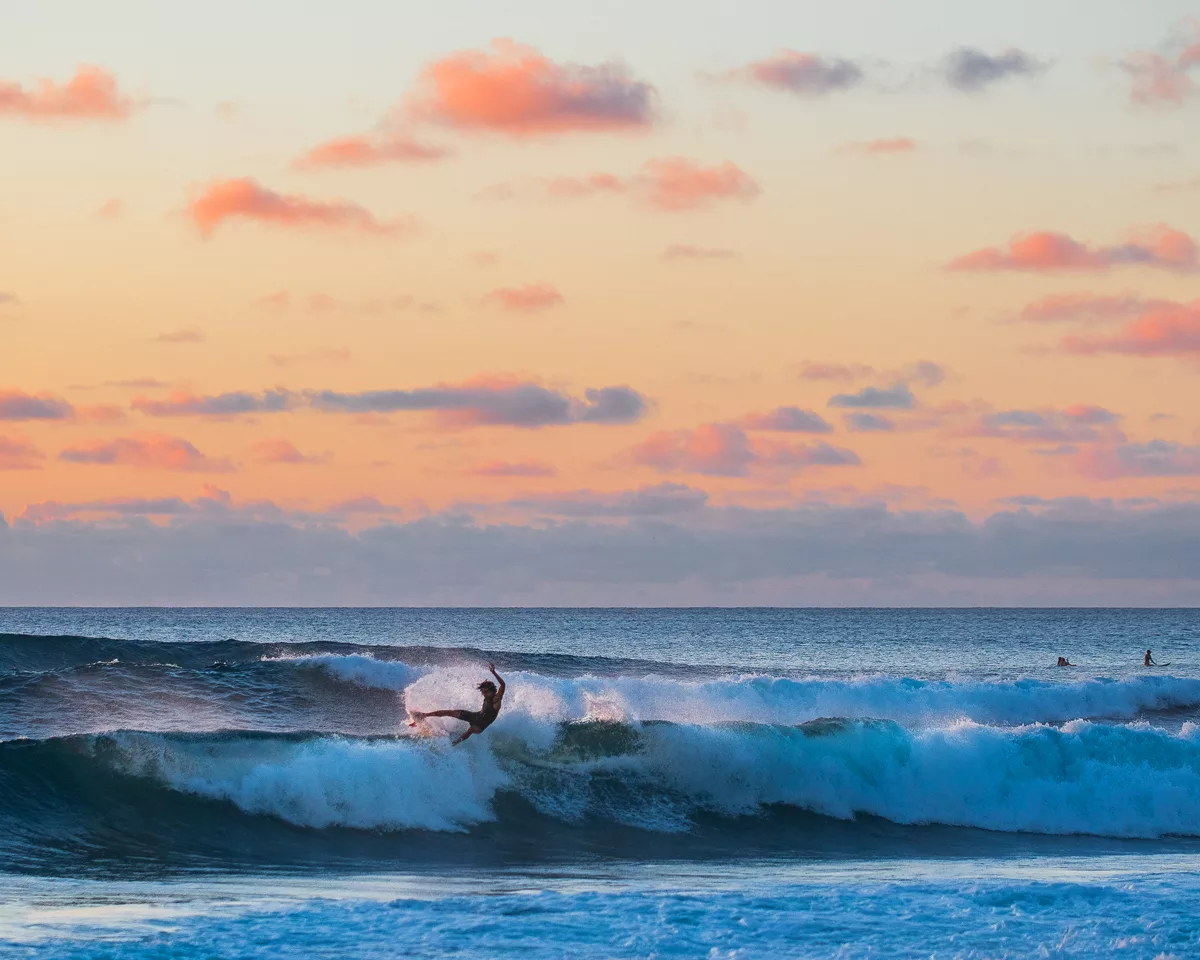 Hawaii surfer shredding a wave at sunset beach.